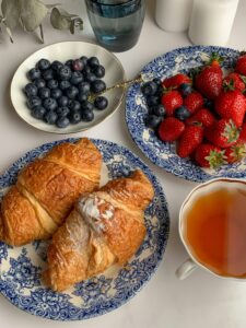 Delicious morning setup with croissants, blueberries, strawberries, and a cup of tea.